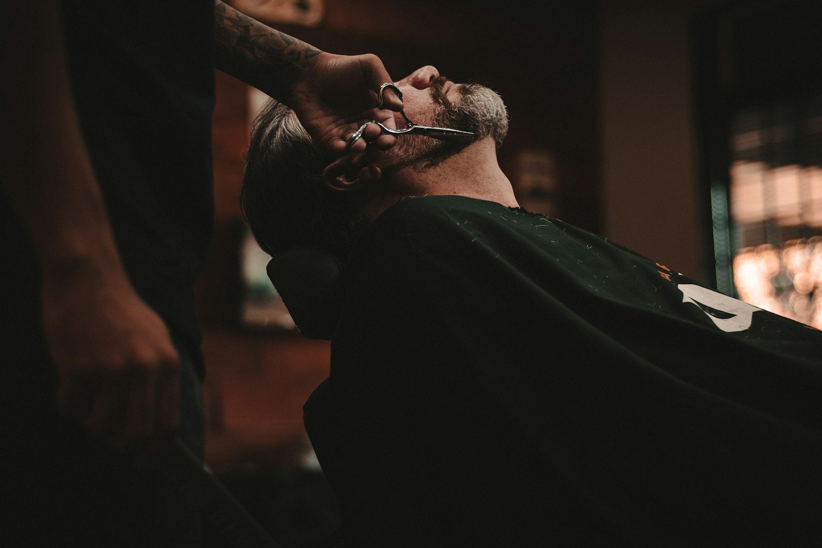 A barber trimming a client's beard